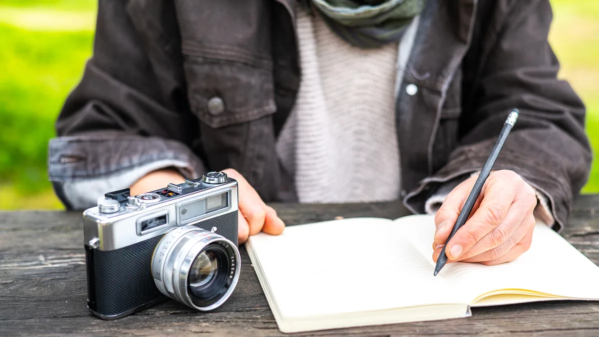 Ahşap masada fotoğraf makinesi ve not defteri