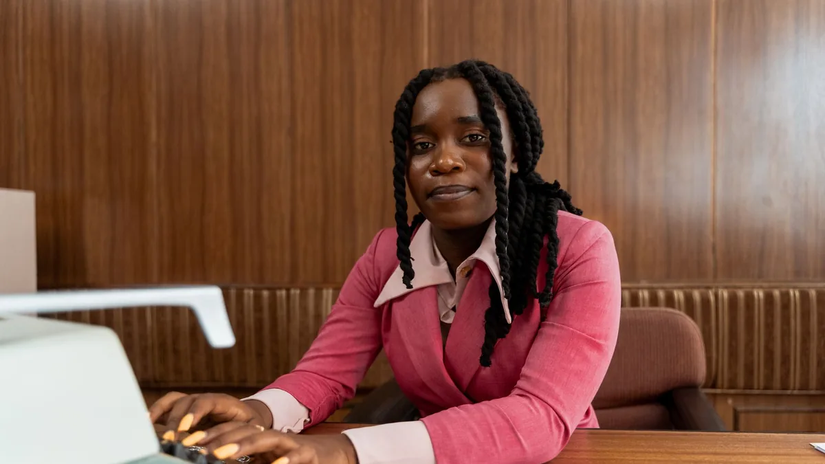 African american woman in a pink suit typing on a retro