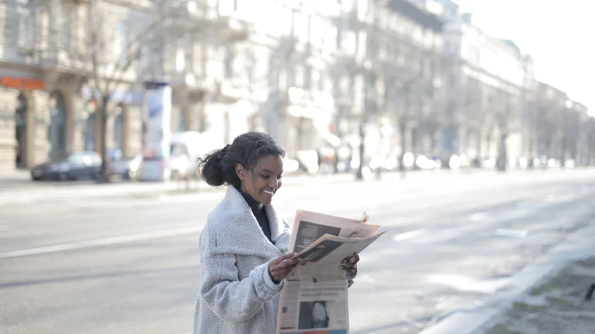 African american woman reading a newspaper on an urban s