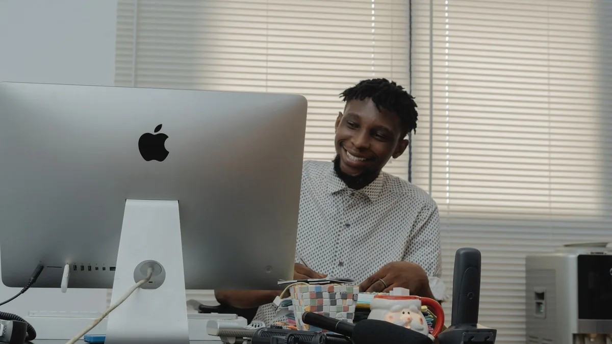 African man smiling while working at a desk with a compu