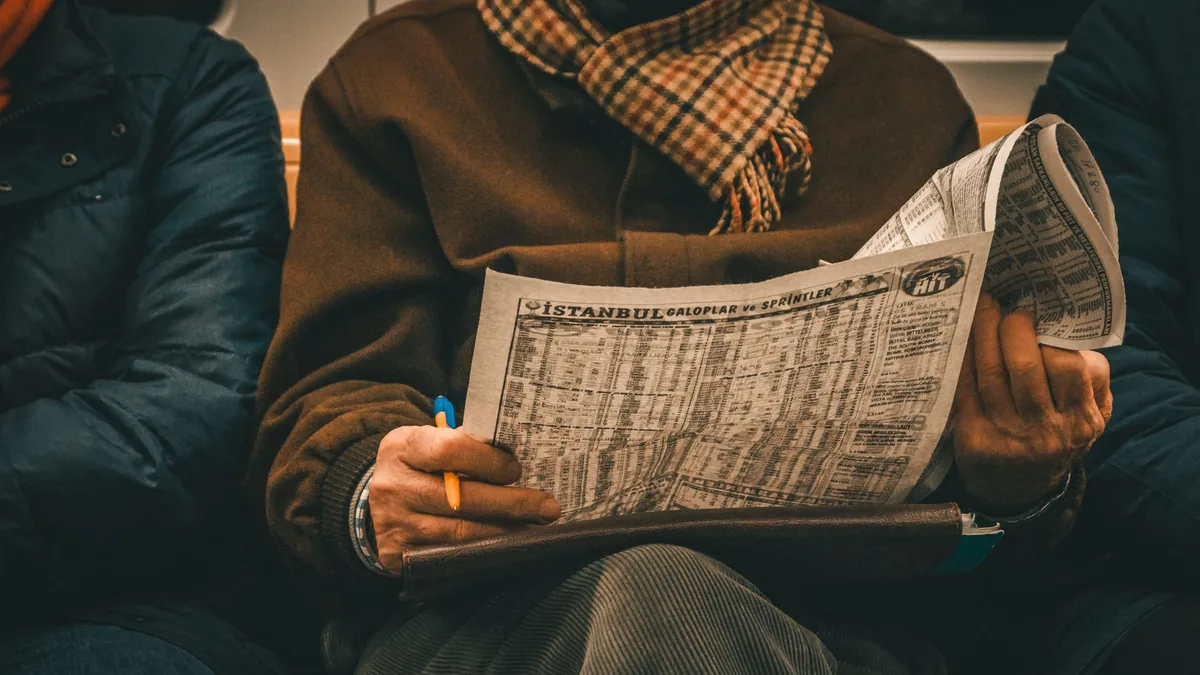 An adult man reads a newspaper showing istanbul train sc