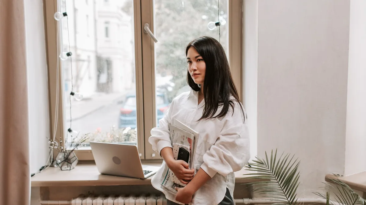Asian woman in white blouse holding newspapers in a mode