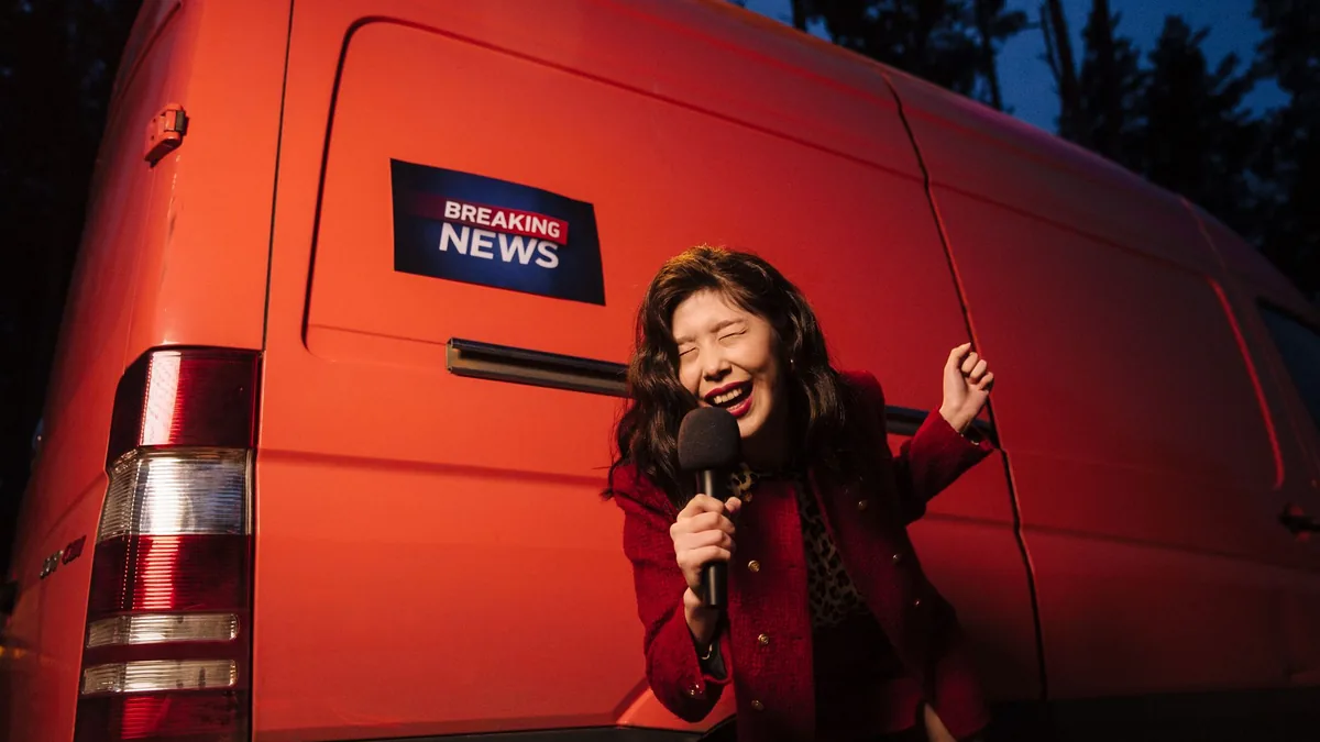 Asian woman reporter energetically broadcasting with a m