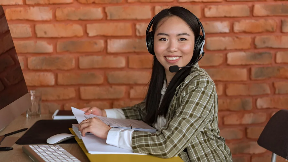 Asian woman working as a call center agent smiling at de