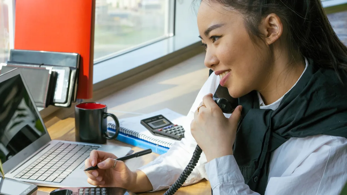 Asian woman working at desk multitasking with a smile