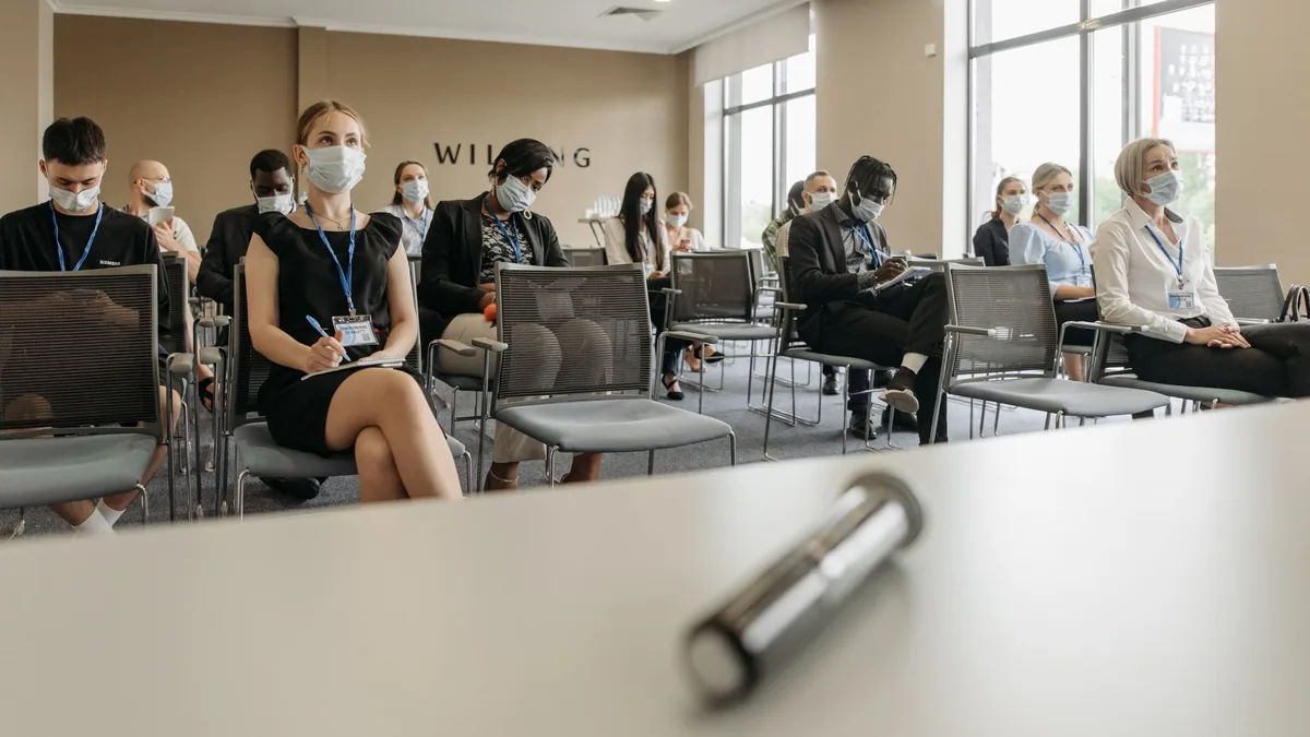 Attendees sit apart wearing masks at a modern business s