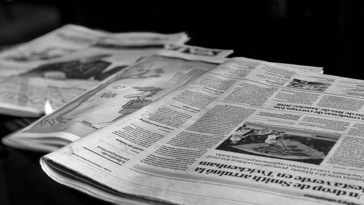 Black and white close up image of newspapers laid on a t