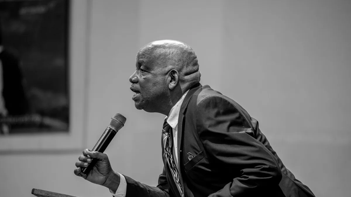 Black and white photo of a speaker at a podium with a mi