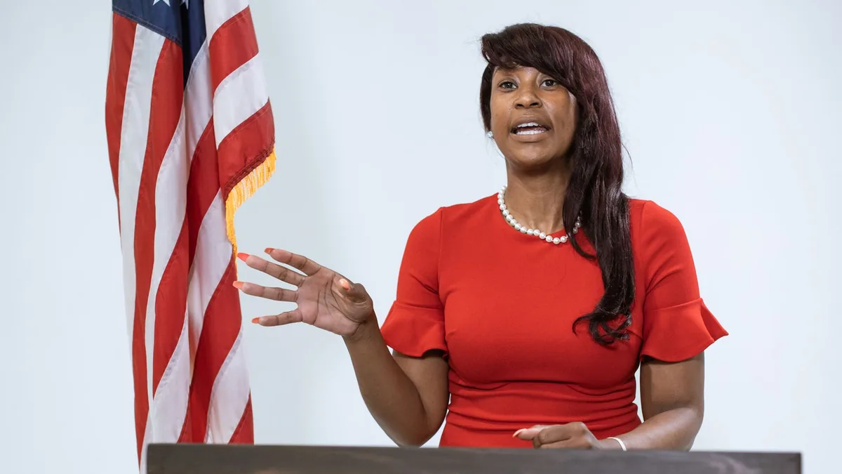 Black woman giving a speech at a podium with an american
