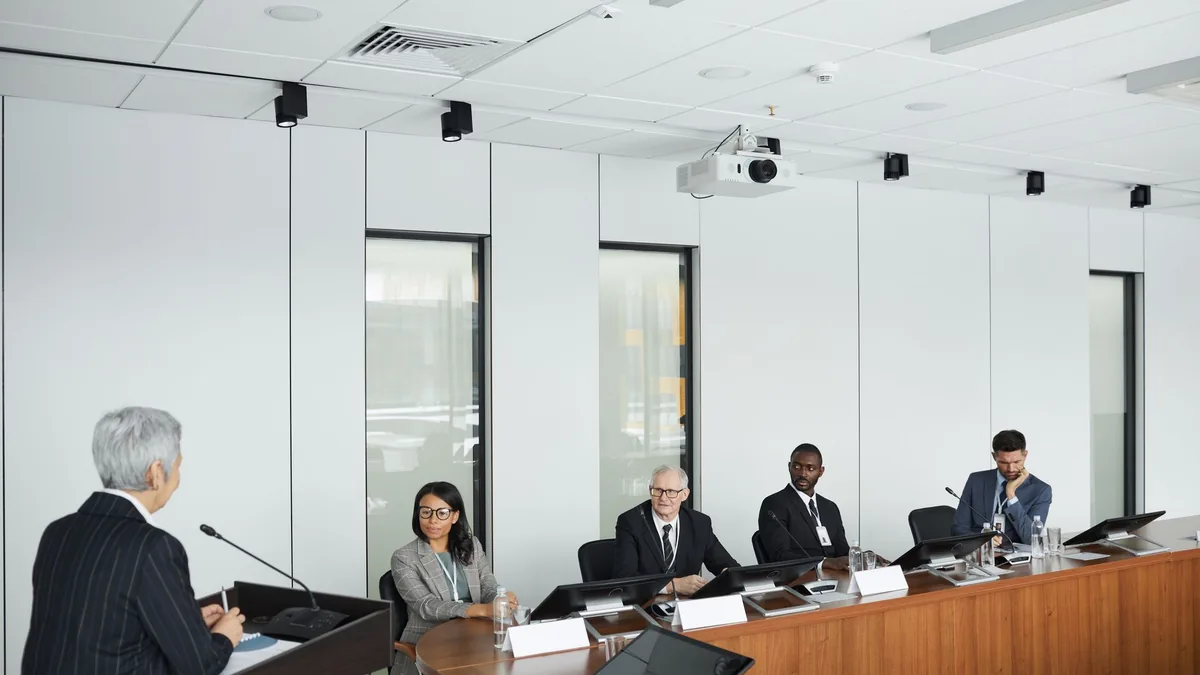 Business meeting with diverse panel and a speaker in a m