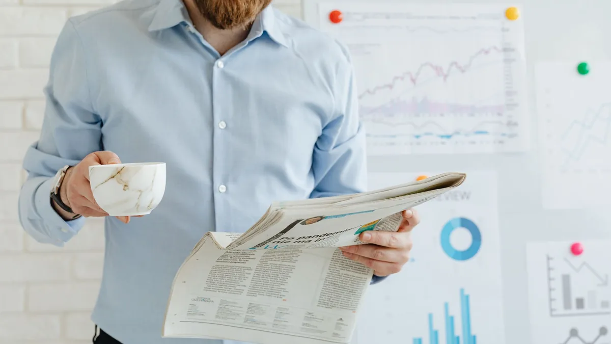Business person holding coffee and newspaper in office w