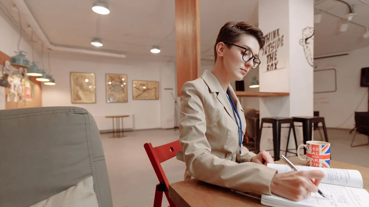 Business professional woman writing in a notebook at a m
