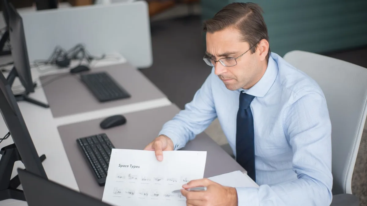 Businessman focused on analyzing documents at desk in of