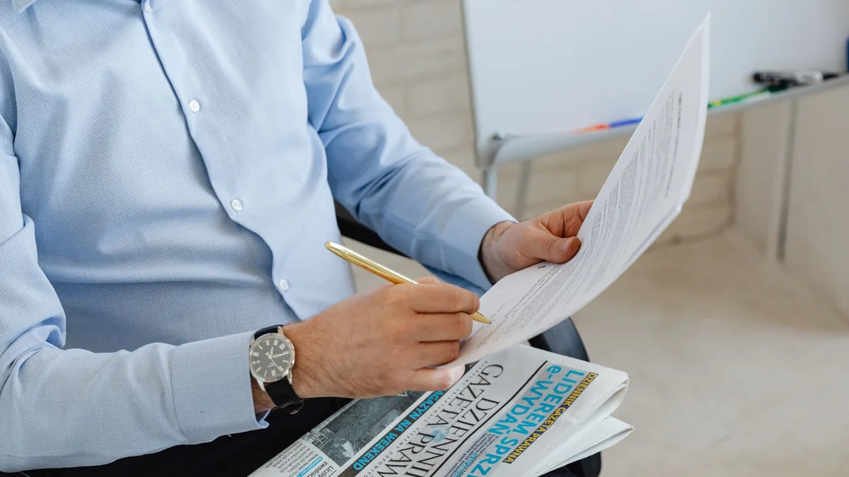 Businessman in blue shirt reviewing documents with a pen