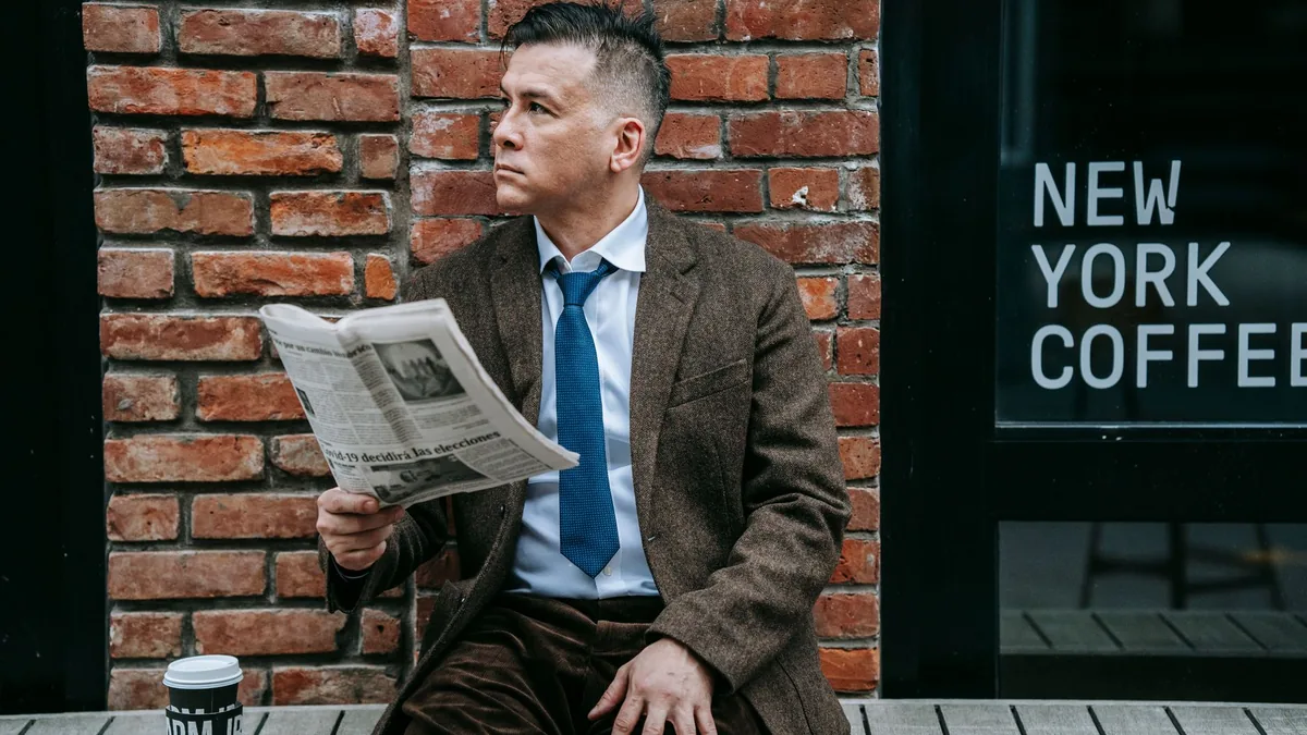 Businessman in formal wear reading newspaper outside cof