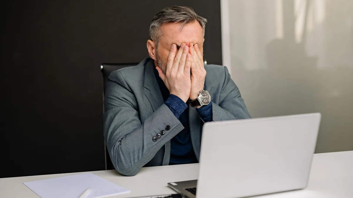 Businessman in gray suit showing frustration while worki