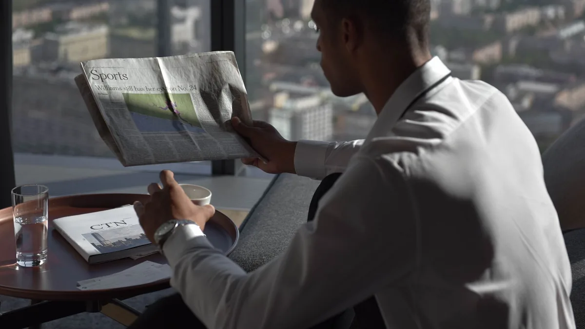 Businessman in office reading sports section enjoying co