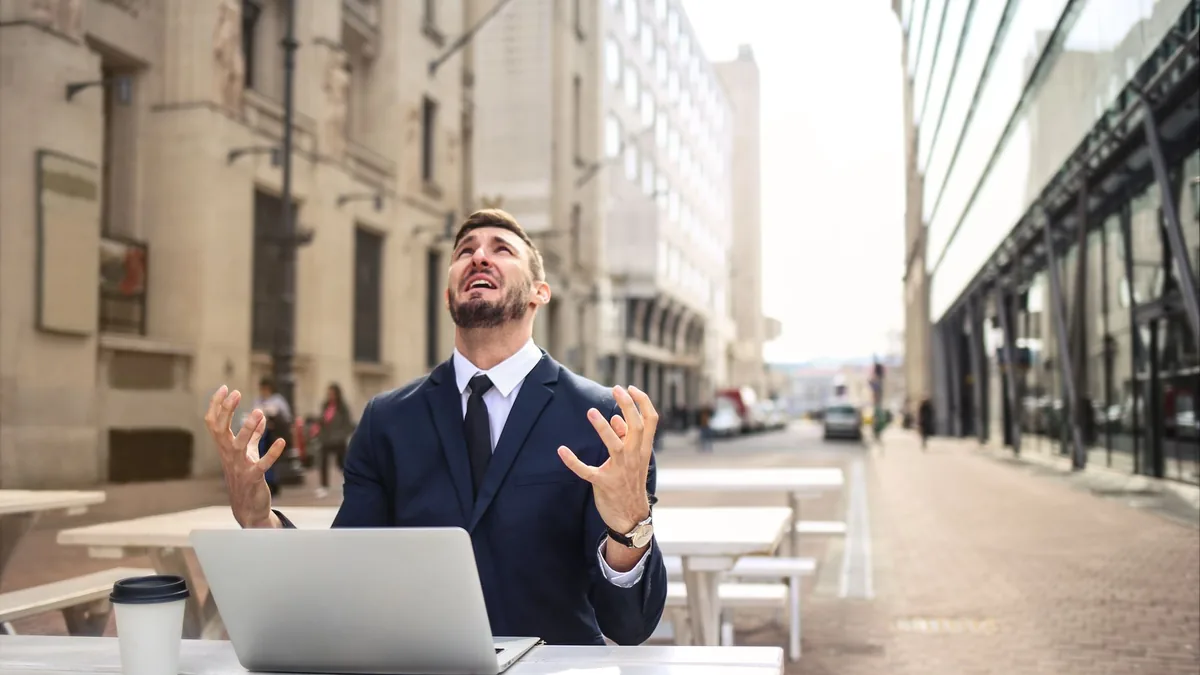 Businessman in suit showing frustration at outdoor table
