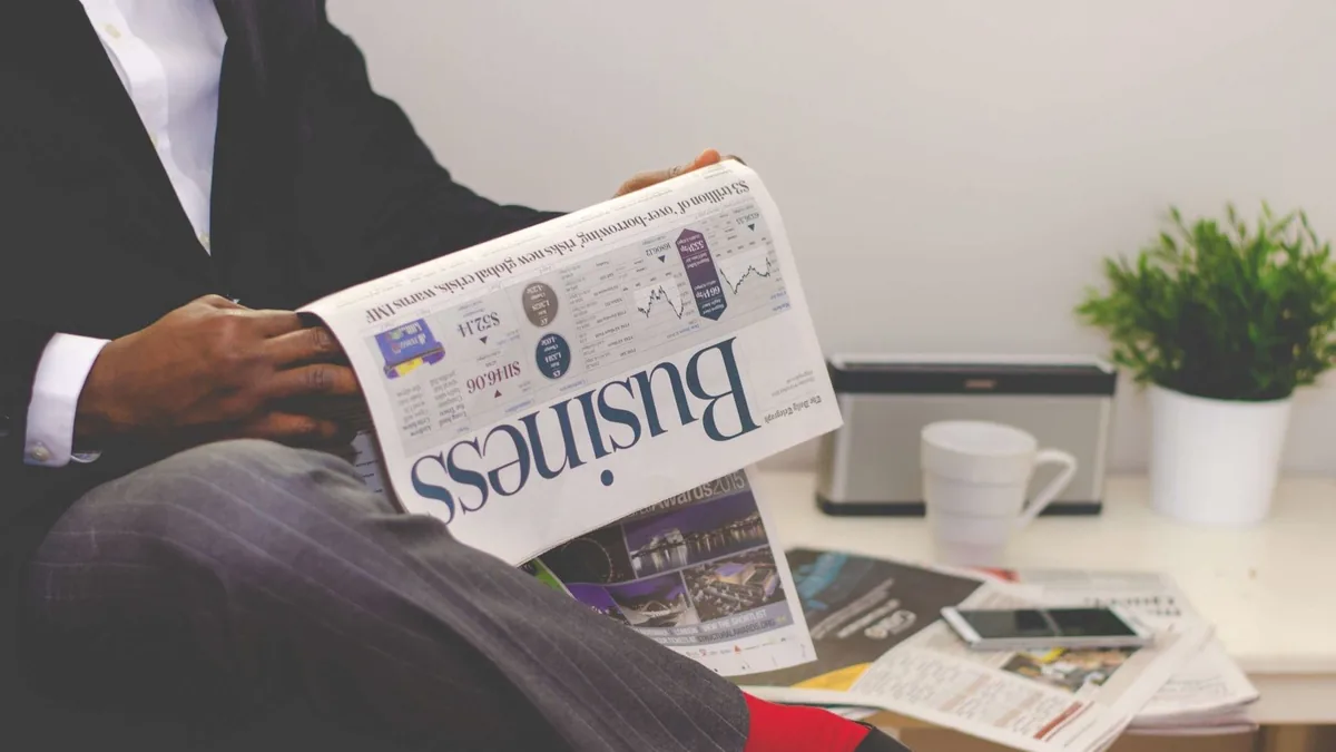 Businessman reading a financial newspaper at a desk high