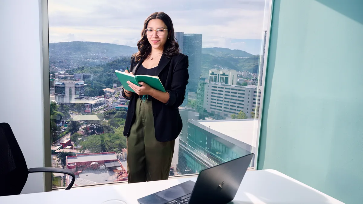 Businesswoman in office holding notebook by window overl
