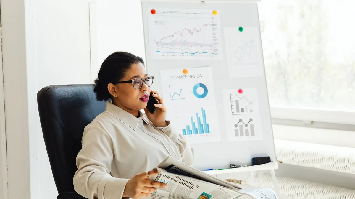 Businesswoman multitasking with phone and newspaper in o