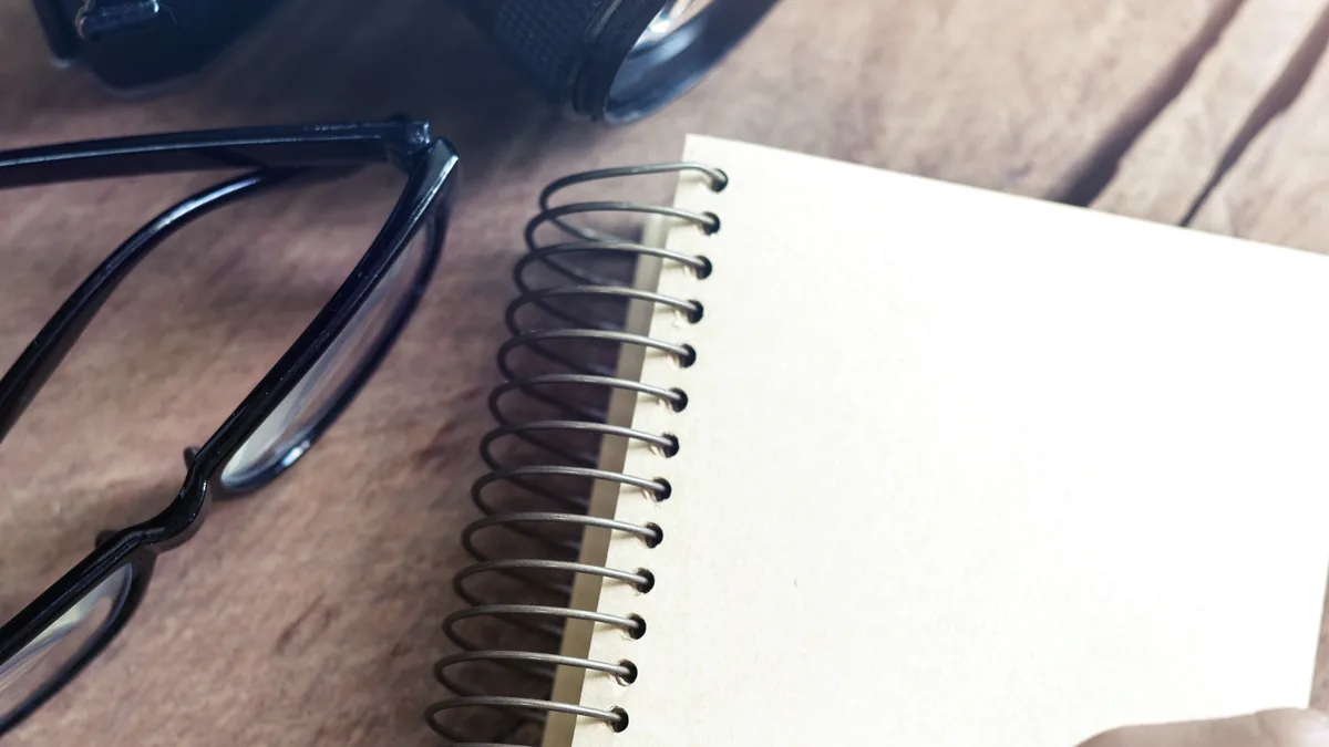 Ahşap yüzeyde fotoğraf makinesi, defter ve kalem