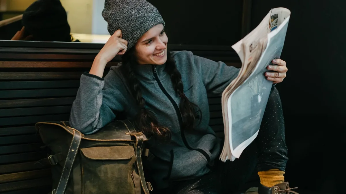 Casually dressed woman enjoying reading a newspaper whil