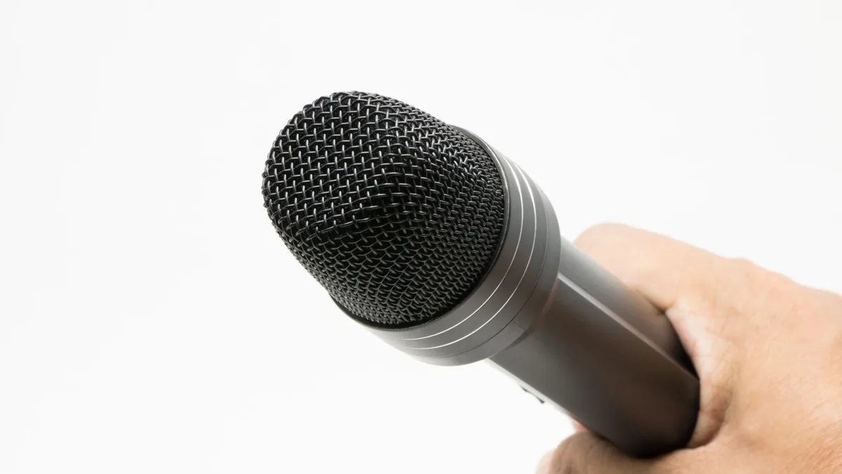 Close up image of a microphone held in hand against a wh