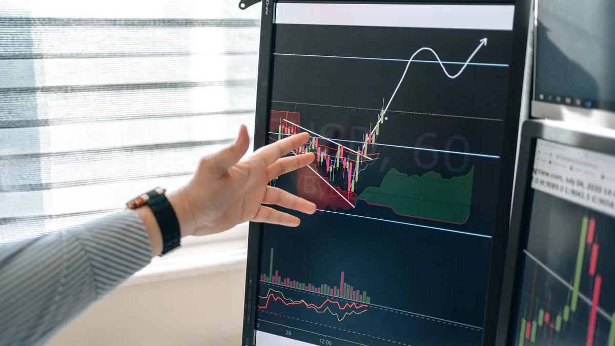 Close up of a hand pointing at stock market graphs on a