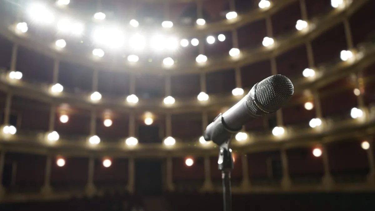 Close up of a microphone on stage with bright theater li