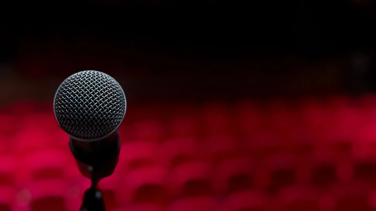 Close up of microphone on stage with empty red seats in