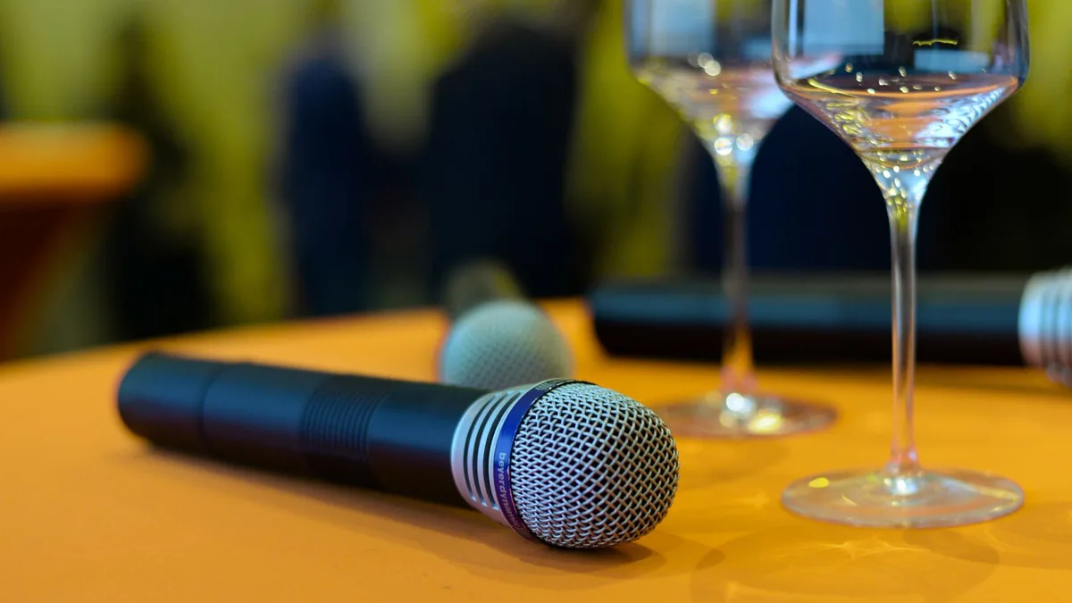 Close up of microphones and wine glasses on an orange ta