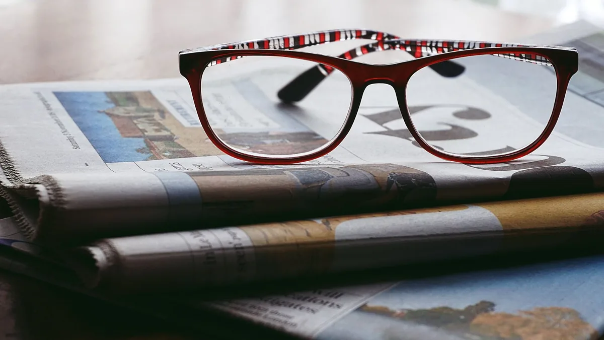 Close up of reading glasses resting on a stack of newspa