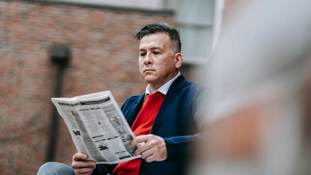 Confident adult man in stylish attire reads a newspaper