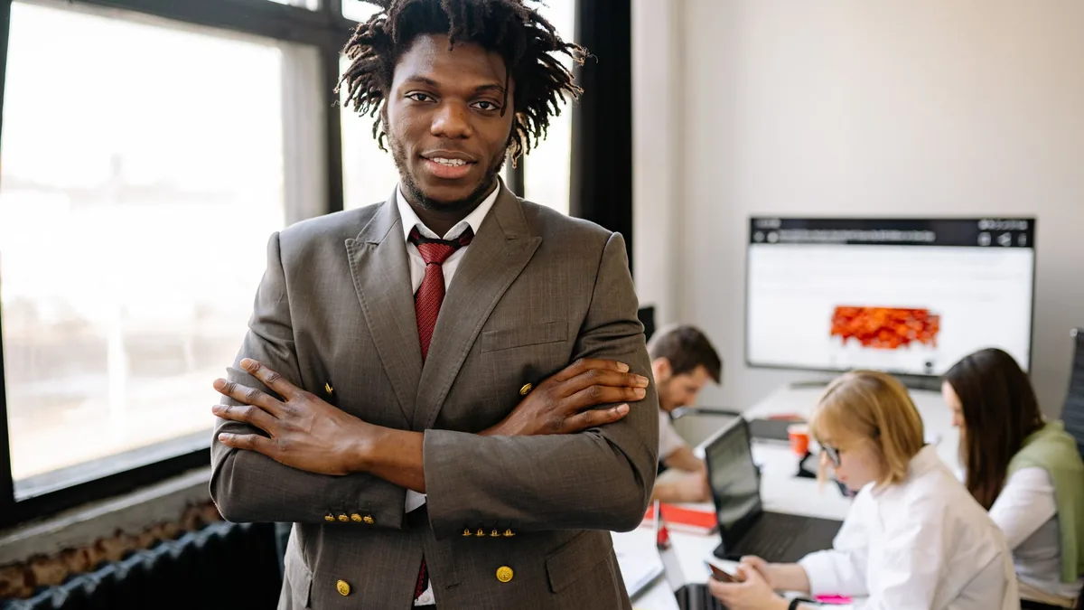 Confident businessman with arms crossed in a bright offi