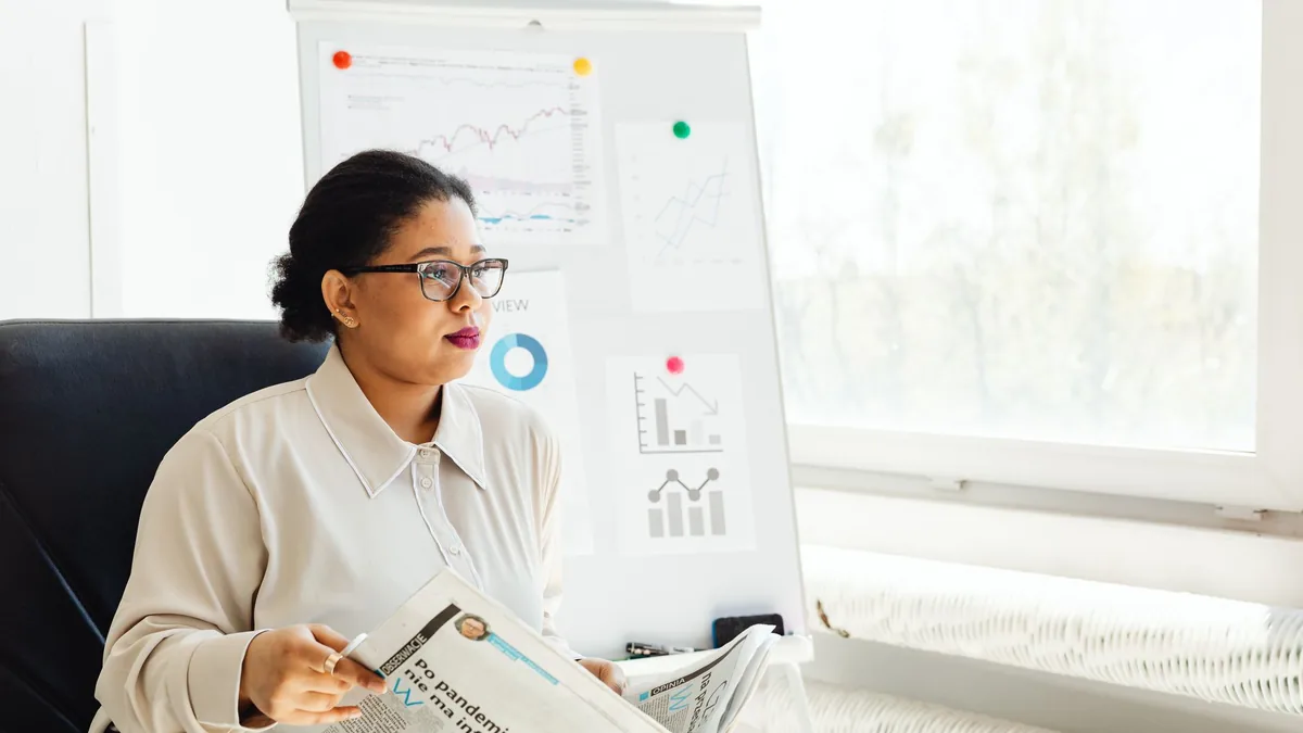 Confident businesswoman reading newspaper and analyzing