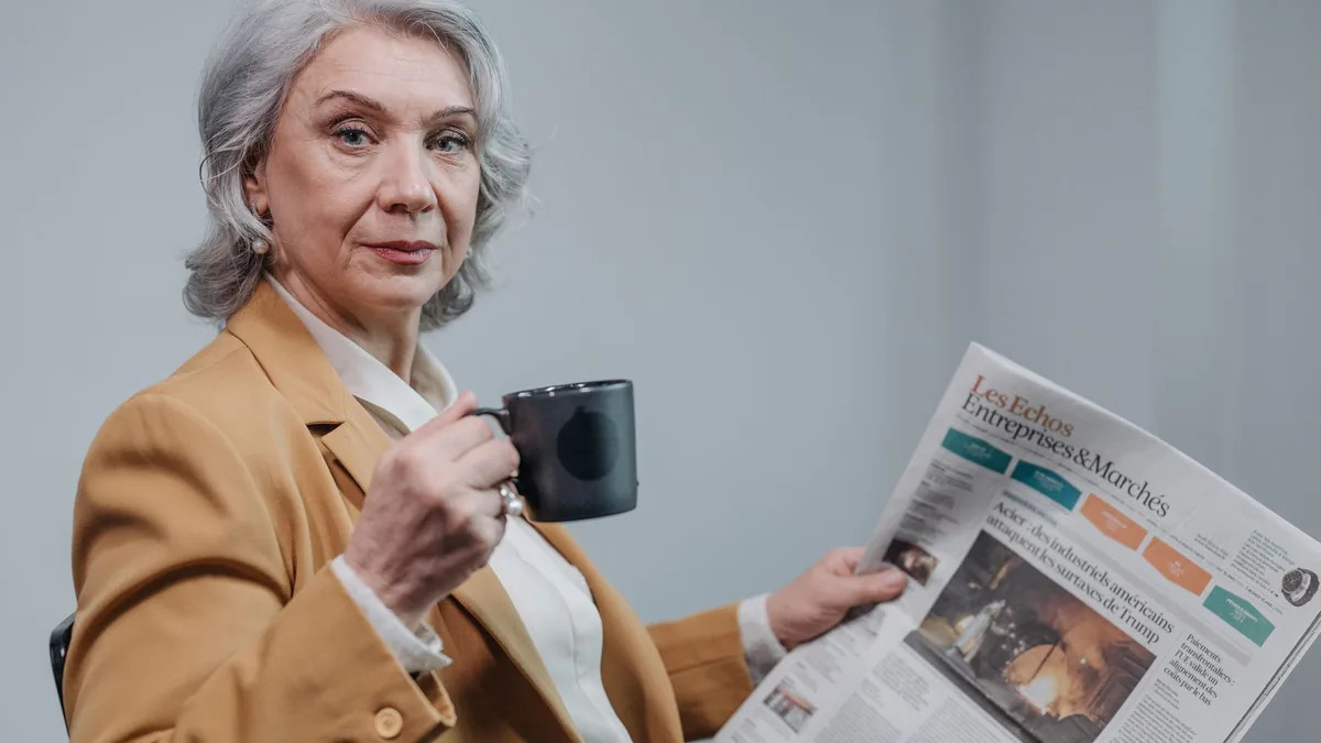 Confident senior businesswoman holding coffee and readin