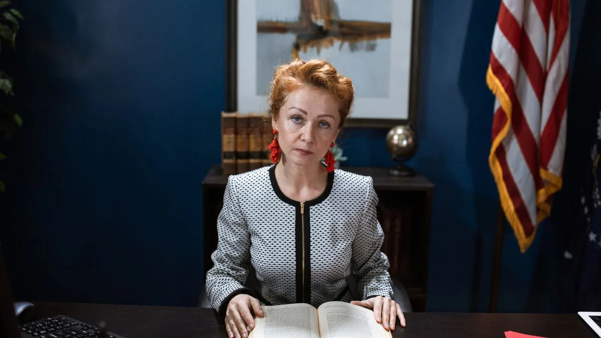 Confident woman in business attire at a desk with an ope