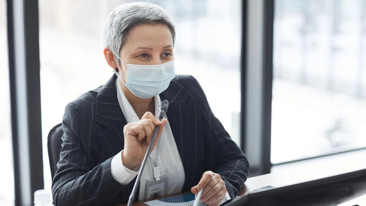 Confident woman in business attire speaking into a micro
