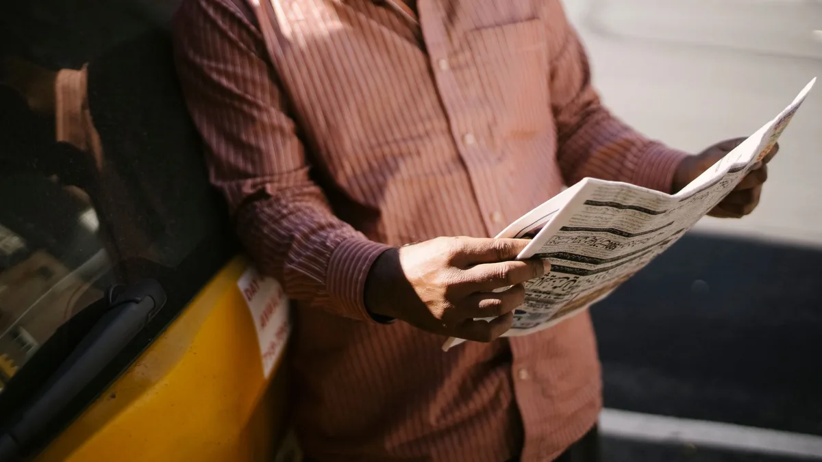 Crop anonymous ethnic cab driver in ornamental shirt sta