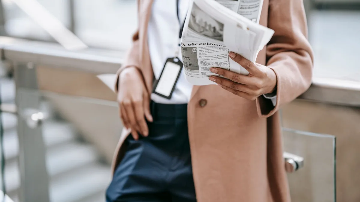 Crop anonymous female entrepreneur in trendy brown coat