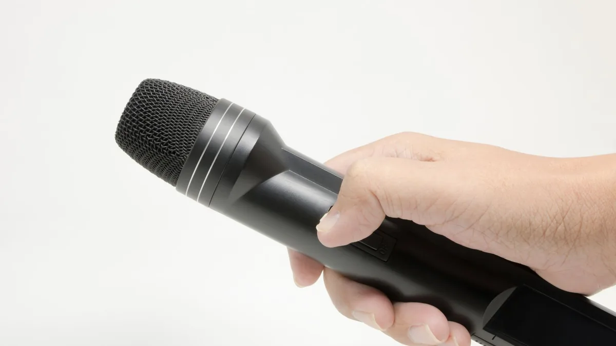 Detailed image of a hand gripping a black microphone iso