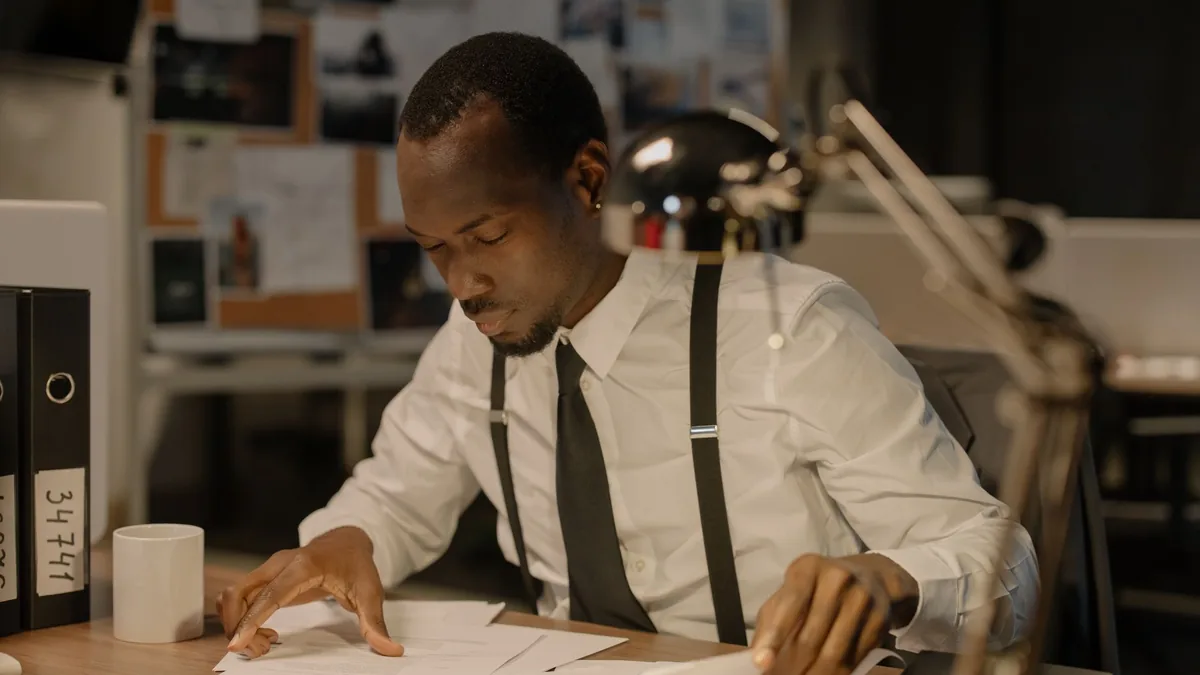 Detective concentrating on documents at desk solving com