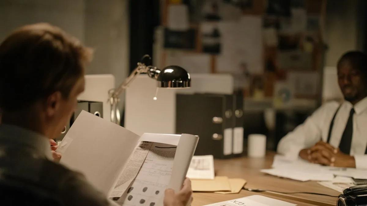 Detectives reviewing documents in a dimly lit office foc