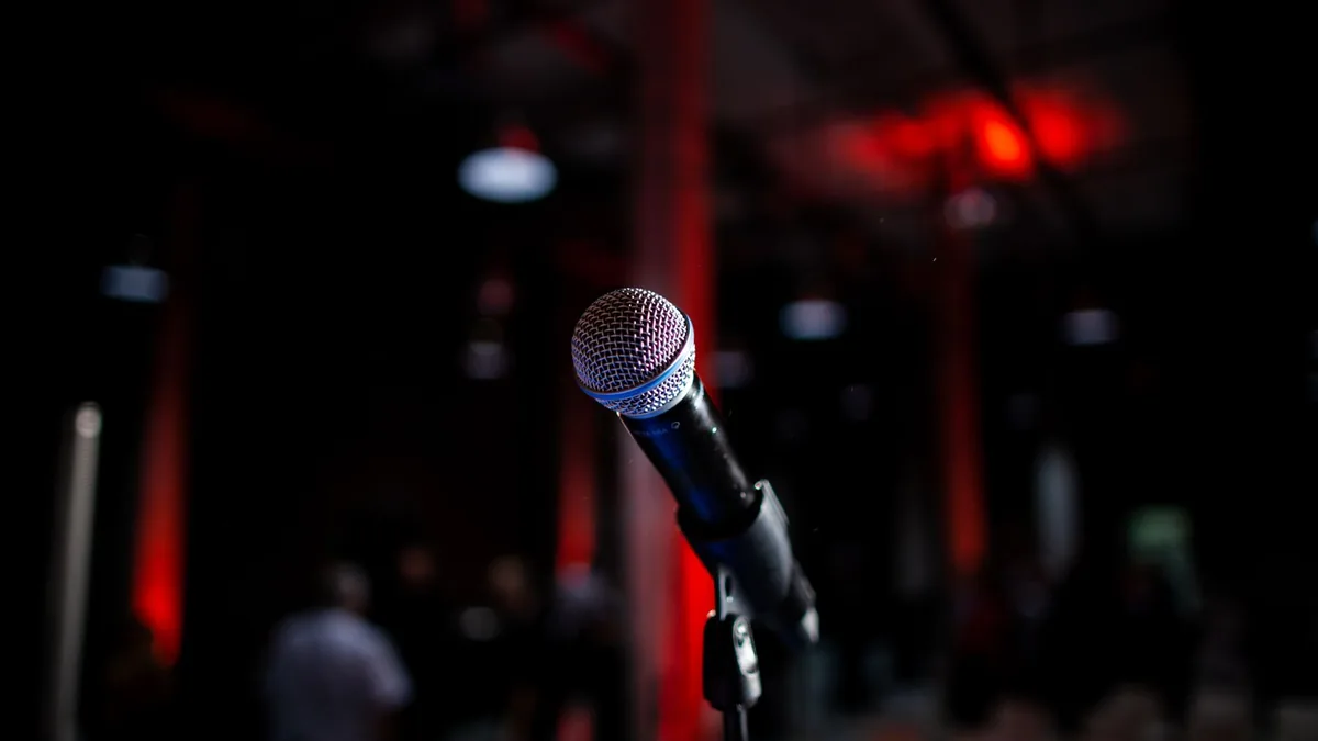 Dynamic photo of a microphone on stage with red backligh