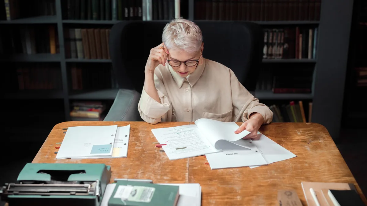 Elderly woman in an office reading and reviewing scripts