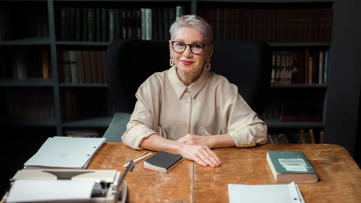Elderly woman with eyeglasses at a library desk surround