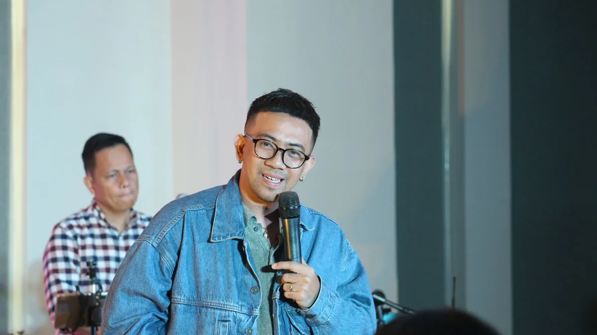 Engaging seminar speaker in denim jacket holding microph