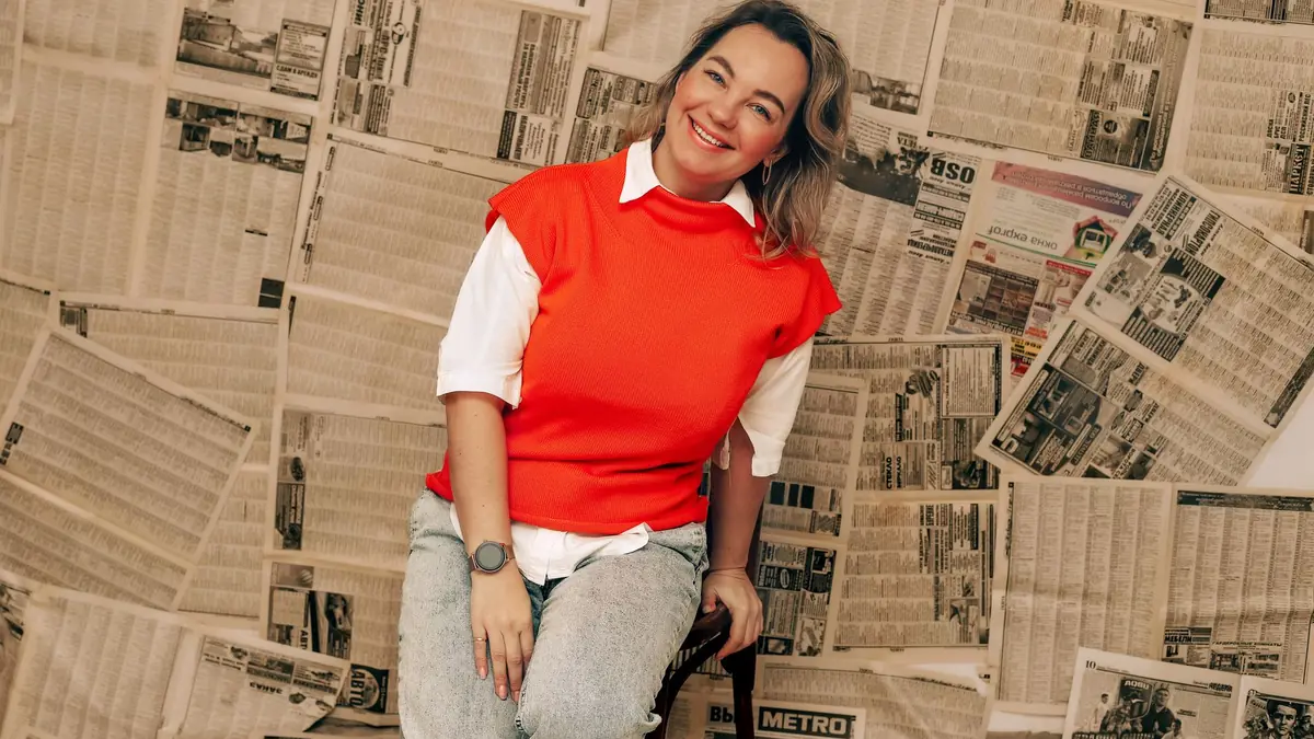 Fashionable woman with a joyful smile sitting against a