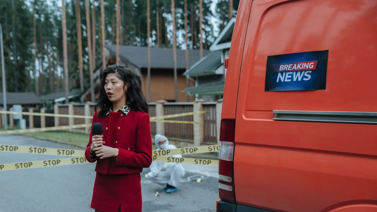 Female reporter in red outfit at an outdoor crime scene